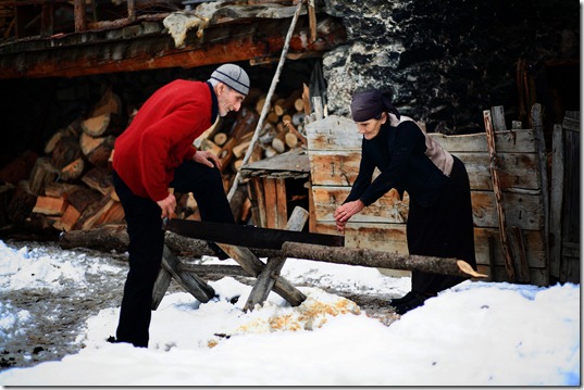 Natalia Qaldani helps her husband saw firewood